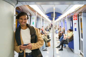 Smiling man commuting by subway using smartphone