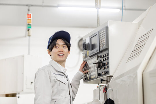 工場の操作盤の前で働く男性作業員