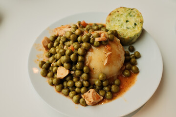 Mashed potatoes topped with green pea stew and chicken pieces on a white plate. Simple comfort food dish, homemade lunch concept with vegetables and protein.