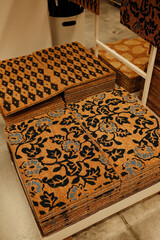 A selection of stacked coir doormats with floral and geometric patterns displayed on a store stand in a home decor section.