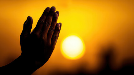 Hands clasped in prayer against a golden sunset.