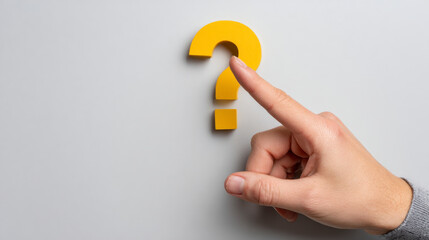 A finger points to a yellow question mark against a gray background.