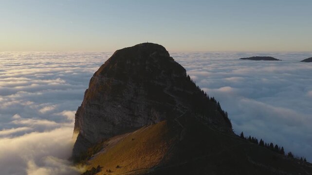 Aerial view of the majestic Dent de Jaman peak piercing through a sea of clouds, bathed in the warm glow of sunrise, Montreux, Vaud, Switzerland.