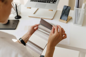 Interior designer reviewing neutral fabric and wallpaper samples