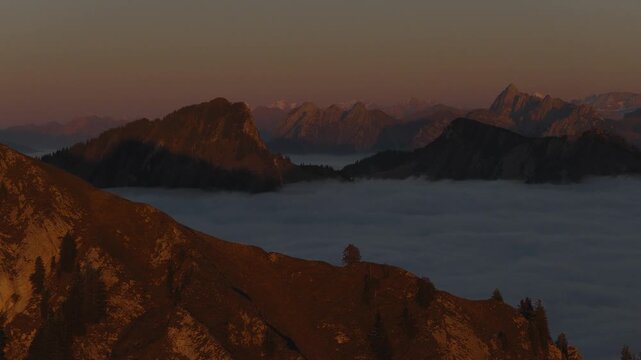 Aerial view of the Dent de Jaman mountains, with its steep slopes and rugged terrain, blanketed by a sea of clouds at sunrise, Montreux, Vaud, Switzerland.