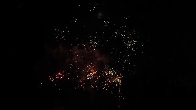 A 10 second high quality clip of vibrant fireworks bursting in a dark night sky. The video features multi colored sparks, smoke effects, and includes the original crackling sound of the explosions