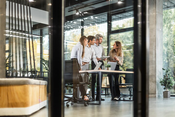 Creative business people, planning and meeting and brainstorming, ideas or strategy at office, view from glass wall.