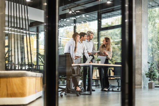 Creative business people, planning and meeting and brainstorming, ideas or strategy at office, view from glass wall.