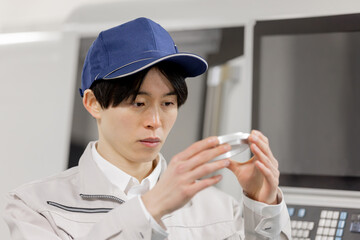 工場で旋盤加工品・フライス加工品を確認する男性作業員