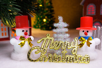 Two white snowmen with letters and a Christmas tree in a Christmas town