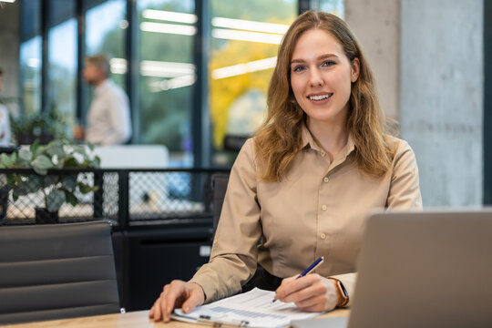 Portrait of happy and successful business woman inside office at workplace, worker smiling and looking at camera with laptop