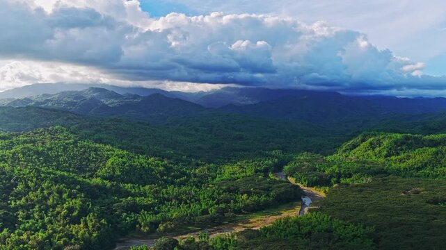 Aerial view of a serene river winding through vibrant green mountains contrasting with the sky, creating a tranquil landscape, Maasin, Western Visayas, Philippines.