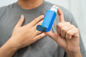 Asthma and chronic obstructive pulmonary disease COPD, Asian young man using metered dose inhaler MDI.