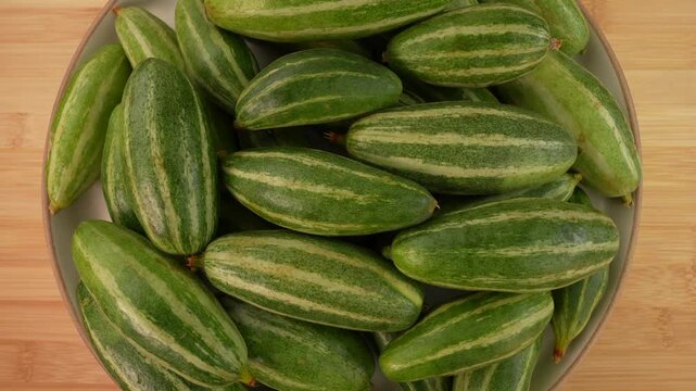 Fresh pointed gourd on plate rotation top view.