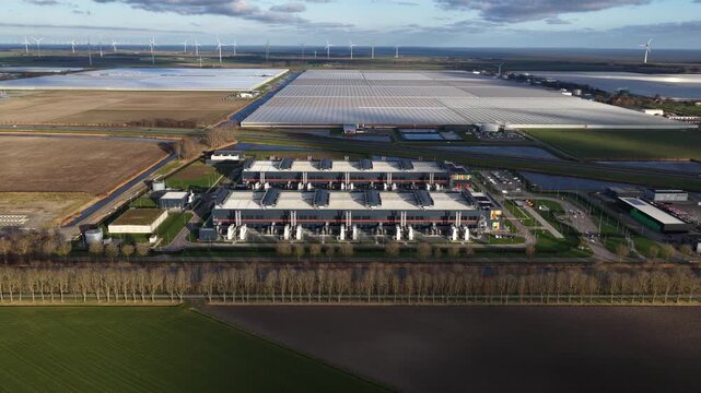 Aerial view of Agriport surrounded by vast greenhouses with symmetrical patterns, contrasting with the green and brown fields, Middenmeer, Noord Holland, Netherlands.
