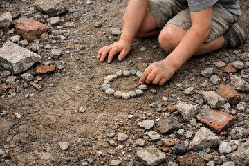 A child creating a circular pattern with stones on a rocky ground