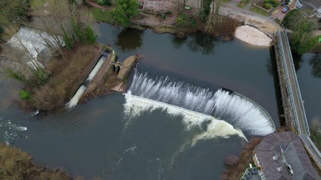 Aerial view of the flowing weir with bridge over the still river waters, contrasting with the surrounding buildings and trees, Derby, England, United Kingdom.