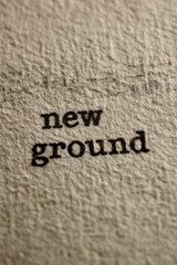 Extreme macro photograph of the words "new ground" typed on thick cream paper, mechanical imprint clear, organic paper grain, understated optimism