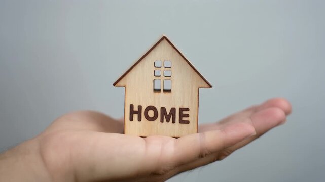 Wooden house labeled &ldquo;HOME&rdquo; on open palm