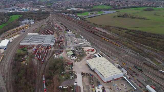 Aerial view of trains and tracks with buildings, vehicles, and greenery around creating an industrial landscape, Nottingham, England, United Kingdom.