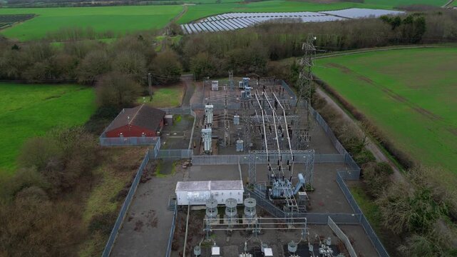 Aerial view of a fenced electricity substation contrasting against a green field and solar panels, Melton Mowbray, England, United Kingdom.