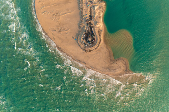 Aerial view of the tip of land meeting the ocean, where the sands shift to a darker hue, contrasting with the surrounding turquoise waters, Dhanushkodi, Tamil Nadu, India.