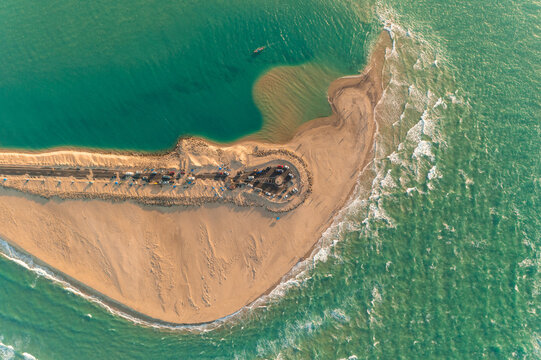 Aerial view of the sandy tip where land meets the turquoise sea, with a visible structure, contrasting the soft beach with the ocean's dynamic hues, Dhanushkodi, Tamil Nadu, India.