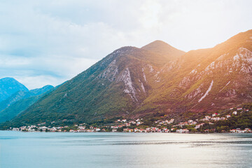 Calm lake reflecting green hills and clouds