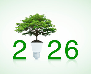 2026 text and big tree on soil with led light bulb over white background, Happy new year 2026 ecology and saving energy concept