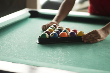 Hands Aligning Pool Balls in Triangle Rack on Green Table
