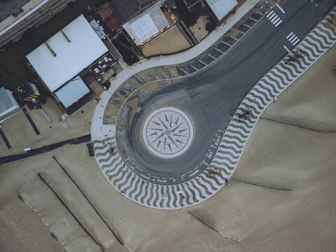 Aerial view of the roundabout with a compass design nestled between sandy shores and buildings, Foz do Arelho, Leiria District, Portugal.