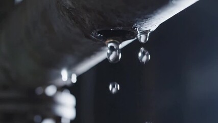 Close-up of dripping water from a faucet, highlighting water conservation and waste