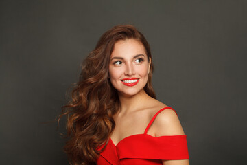 Posing woman with long hair and make-up on black background. Gorgeous woman with curly hairstyle