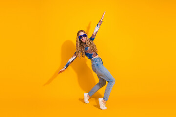 Young woman dancing against bright yellow background showcasing fashion lifestyle joy and energy in casual style for advertising and promo