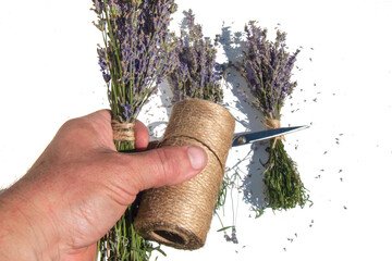 Florist hands creating a lavender bouquet using jute twine, white background