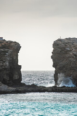 Malta Blue Lagoon landscape. Stunning view of the Blue Lagoon in Comino, Malta, showing the famous turquoise crystal clear waters and the rocky islet of Cominotto under a cloudy sky.