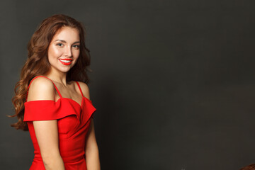 Studio portrait of fashion model woman with shiny skin, wavy hairstyle and red lips makeup on black background