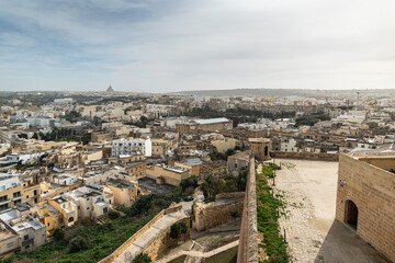 Gozo citadella. Scenic view of the ancient stone fortifications and rooftops within the Cittadella of Victoria, Gozo, showing green grass and traditional limestone architecture.