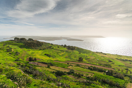 Panoramic view of the terraced green fields and rural landscape of Gozo, Malta, overlooking the Mediterranean Sea and the distant island of Comino