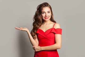 Confident woman holding empty open palm hand and looking at camera on white background