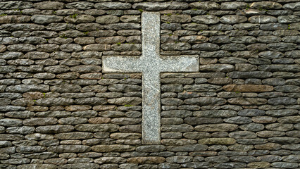Stone cross symbol on old stacked rock wall representing faith and spirituality.