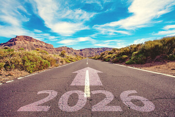Road under blue sky with white clouds. Empty road with written 2026 and arrow pointing towards the horizon to represent the future, positivity and success of the New Year 2026 concept