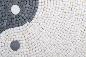 Yin Yang Harmony in Stone Mosaic: A close-up view of a beautifully crafted Yin and Yang symbol rendered in a mosaic of gray and white stones.