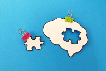 Missing puzzle piece completing a brain symbol on blue background. Mental health and problems with memory.	