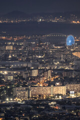 Obraz premium Illuminated Ferris Wheel with Osaka Harbor Cityscape at Dusk