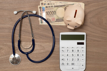 聴診器と電卓と紙幣で医療費のイメージ