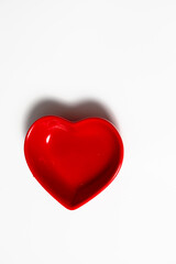 Obraz premium Red heart shape dish on a white background. Symbol of love and romance, ideal for Valentines Day, wedding or Mothers Day.