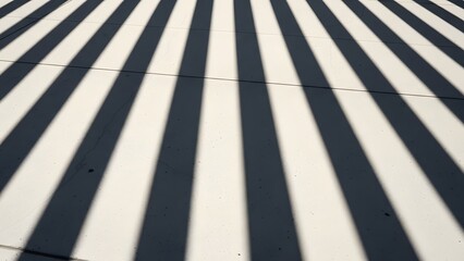 Geometric pattern created by the shadows of modern architectural louvers falling precisely onto a smooth, matte concrete wall during midday sun