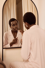 Woman Applying Lip Gloss While Looking in Mirror