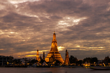 Naklejka premium An abstract, blurred background of nighttime lights along the Chao Phraya River in Bangkok, with Wat Arun, a popular tourist attraction visited by travelers from around the world, in the background.